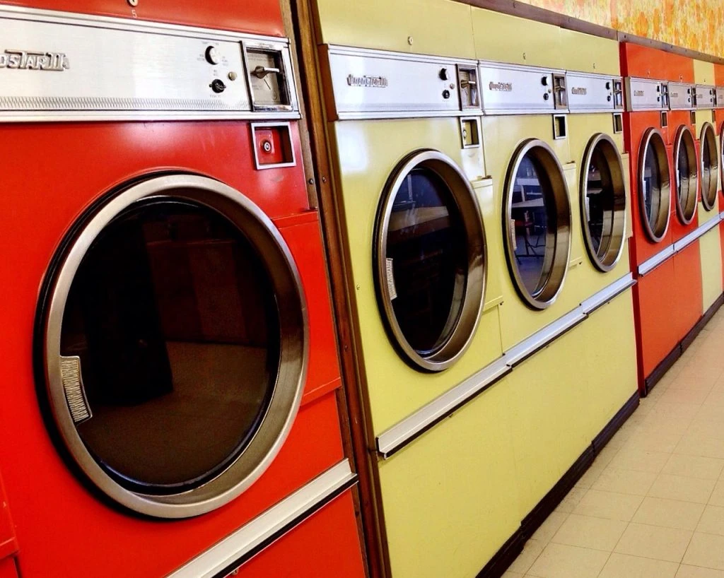 A laundry machine in a dry cleaning facility with clothes ready for delivery in the foreground.