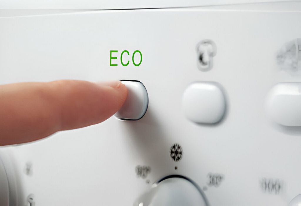 A finger pressing the ECO button on a white appliance control panel, symbolizing a step towards greener dry-cleaning.